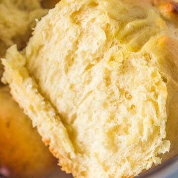 Close-up of a golden, flaky biscuit split open to show its soft, fluffy texture inside.