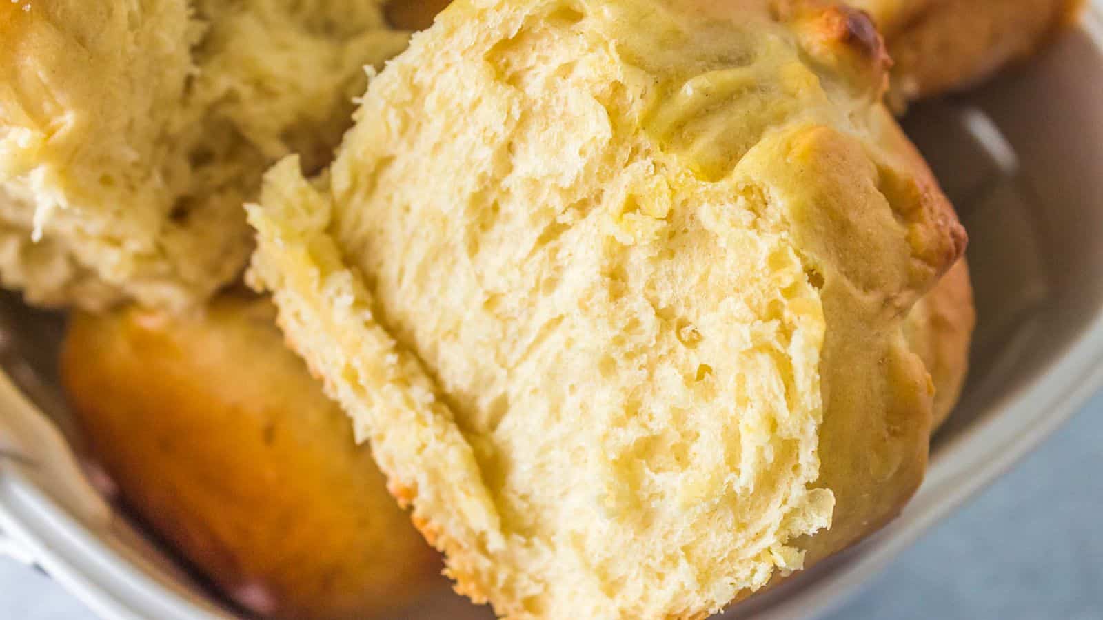 Close-up of a golden, flaky biscuit split open to show its soft, fluffy texture inside.