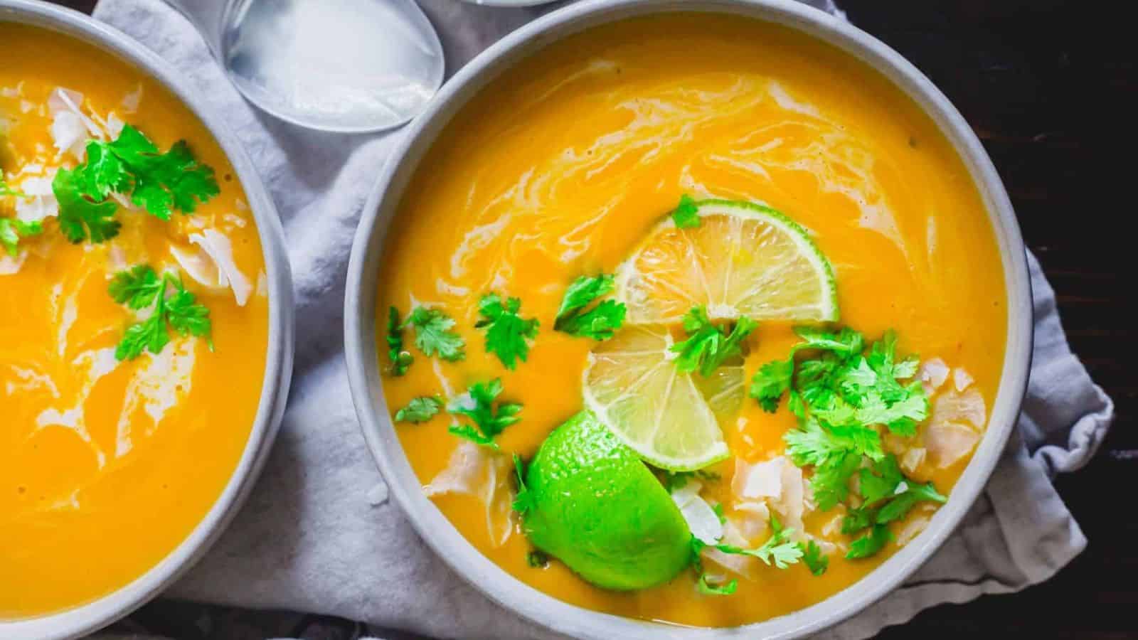 Two bowls of Thai buttercup squash soup with lime and cilantro.