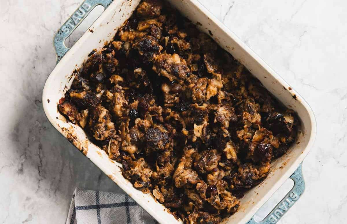 A baking dish filled with browned, gluten free stuffing sits on a marble countertop.