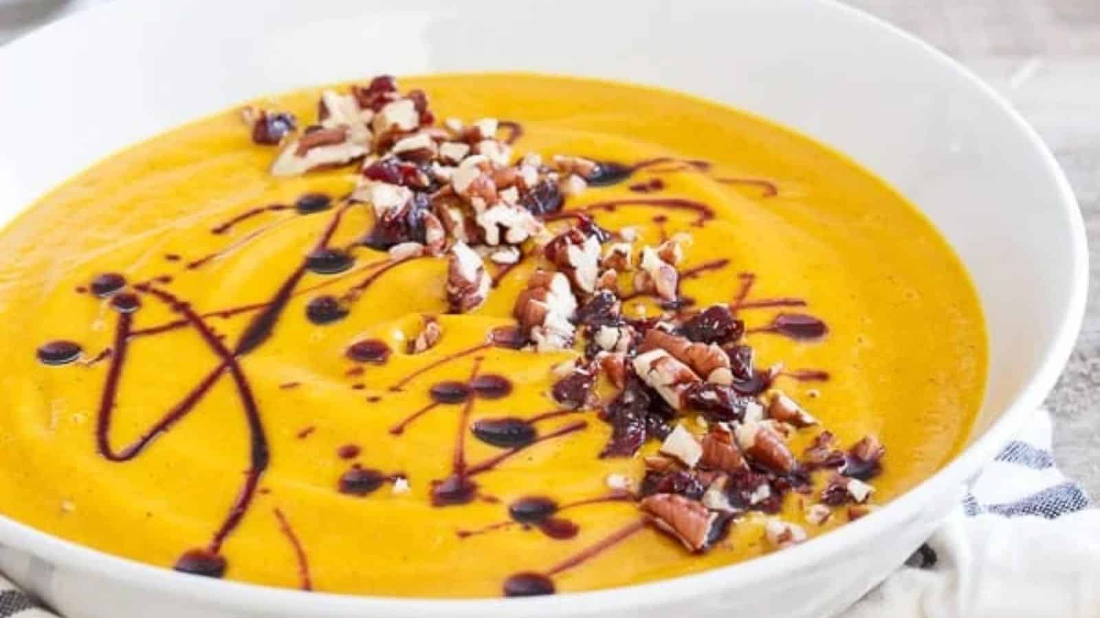 A bowl of kabocha squash soup with cherries and pecans.