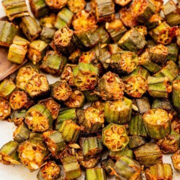 Fried okra pieces on a white plate with a wooden spoon.