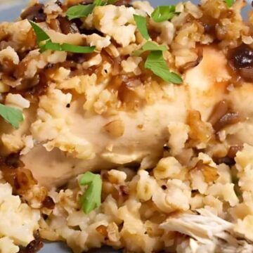 Baked chicken breast topped with rice, caramelized onions, and parsley on a blue plate.