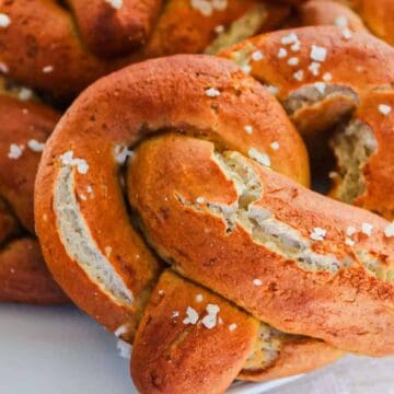 Golden brown soft pretzels topped with coarse salt on a white plate.