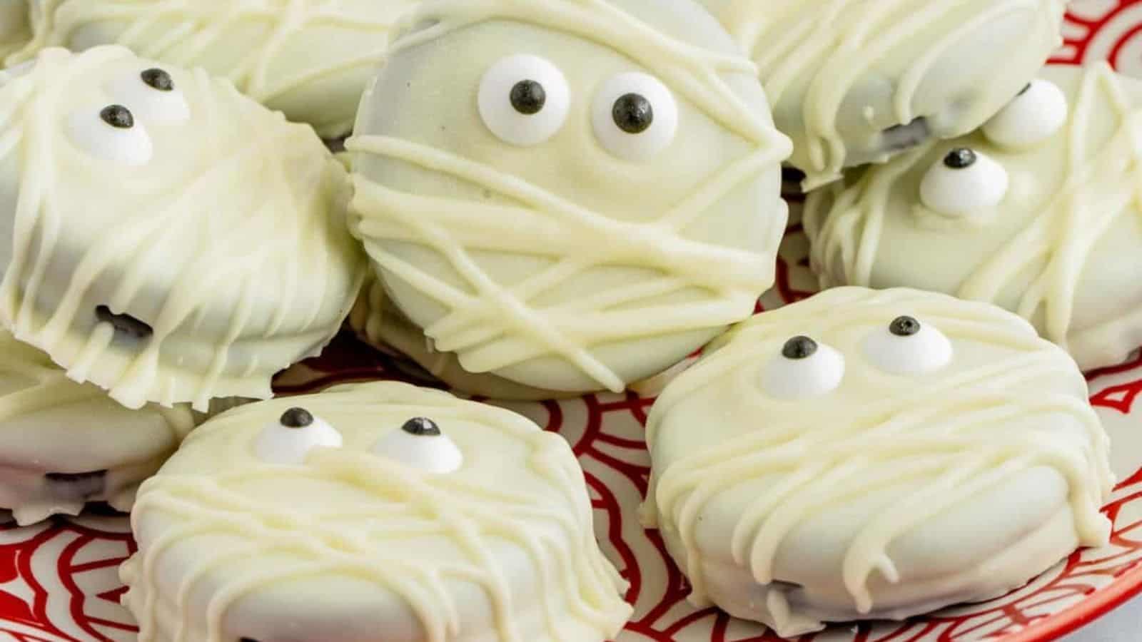 Mummy cookies on a red plate with eyes on them.