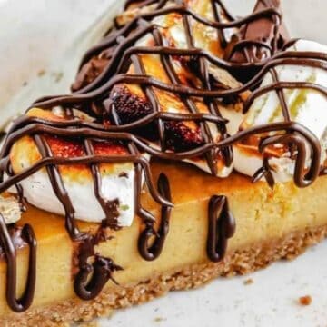 A slice of pie topped with toasted marshmallows and chocolate drizzle on a plate.