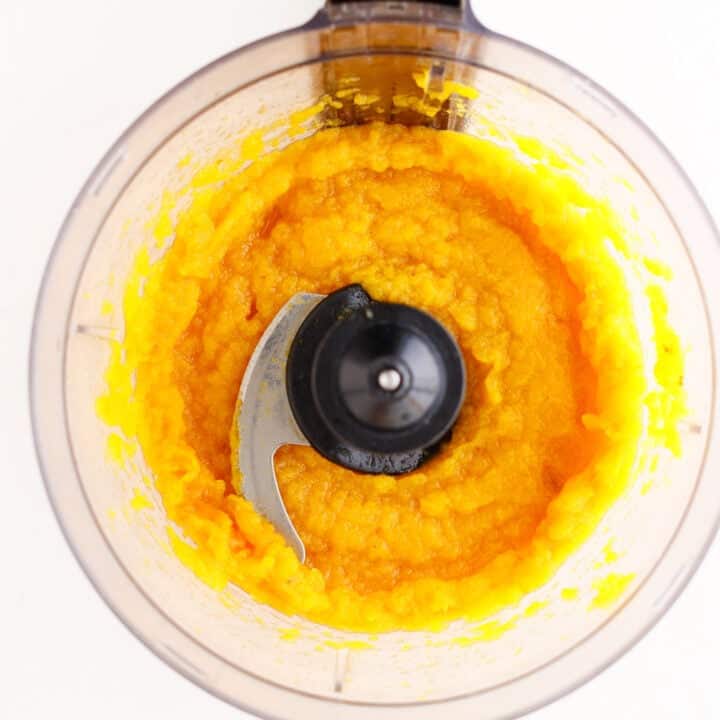 Vibrant orange pumpkin puree in a food processor, viewed from above, ready for your favorite Pumpkin Puree recipes.