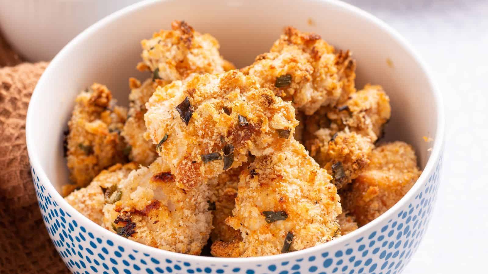 A bowl of golden brown popcorn chicken on a table.