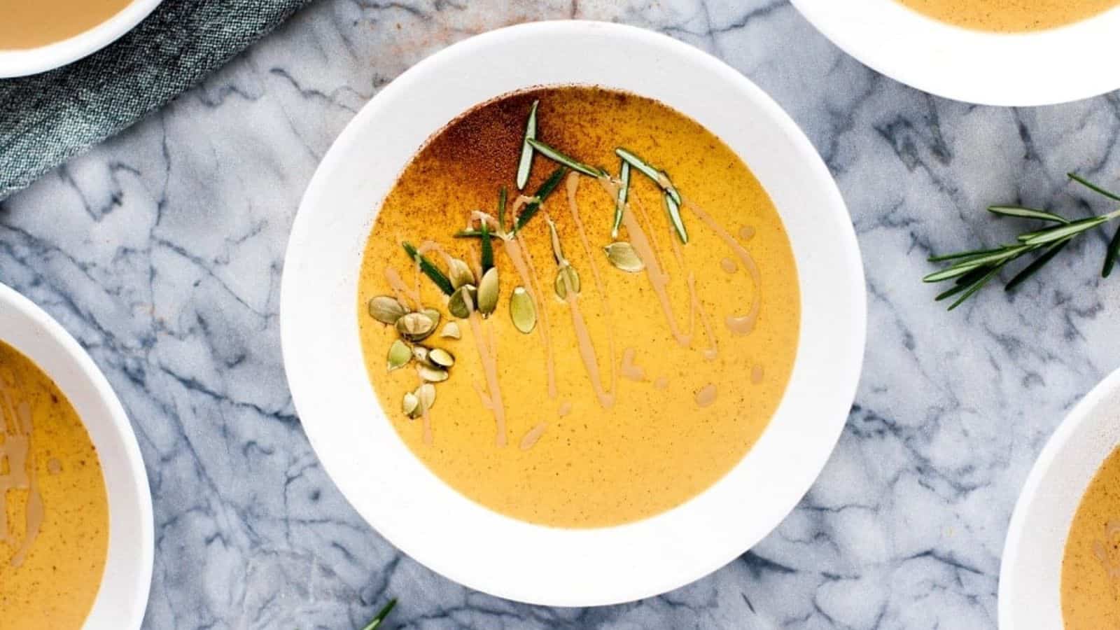 Bowls of pumpkin soup with sprigs of rosemary.