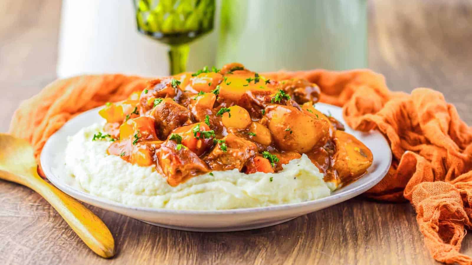 A ladle of beef stew with carrots, potatoes, and parsley in a rich brown sauce.