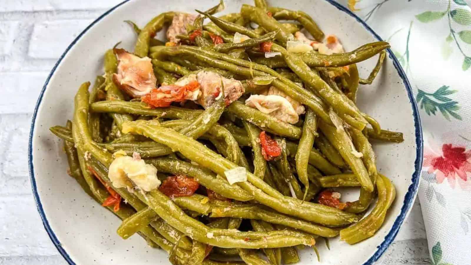 Green beans with pork on a black plate.