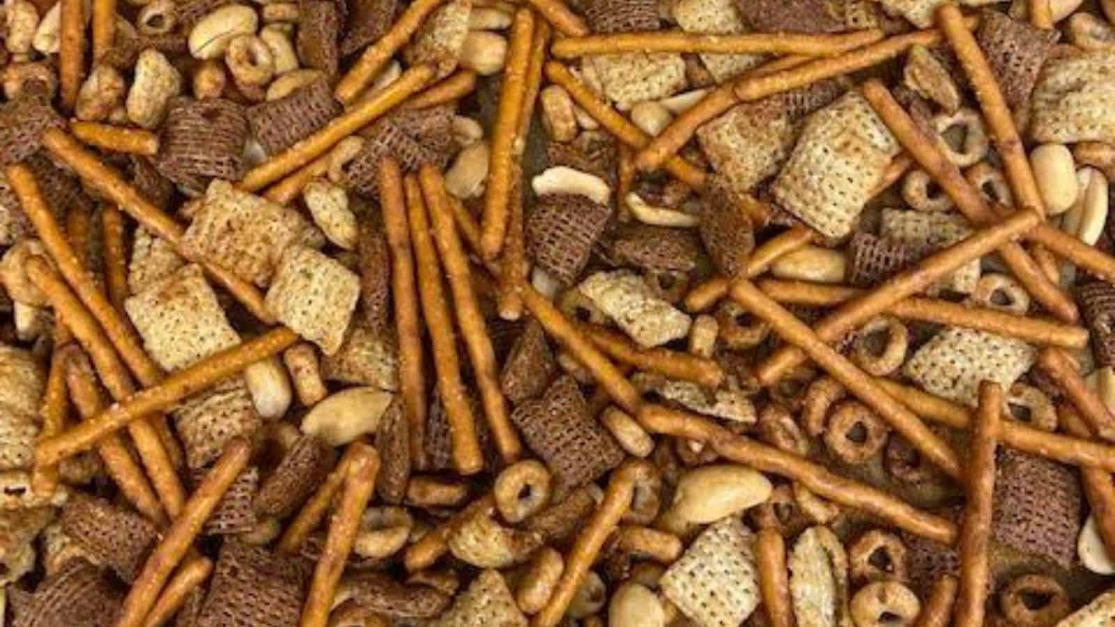Close up of snack mix made up of Chex, pretzels, peanuts, and Cheerios.