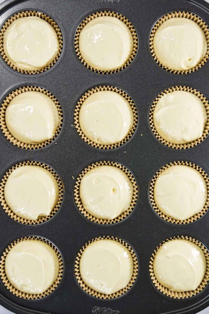 A muffin tin filled with cupcake liners and raw batter ready to be baked.