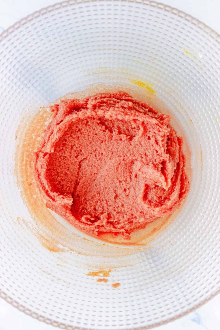 A glass bowl with pink cake batter mixed inside, seen from above&mdash;perfect for whipping up unique treats like Pumpkin Macarons.