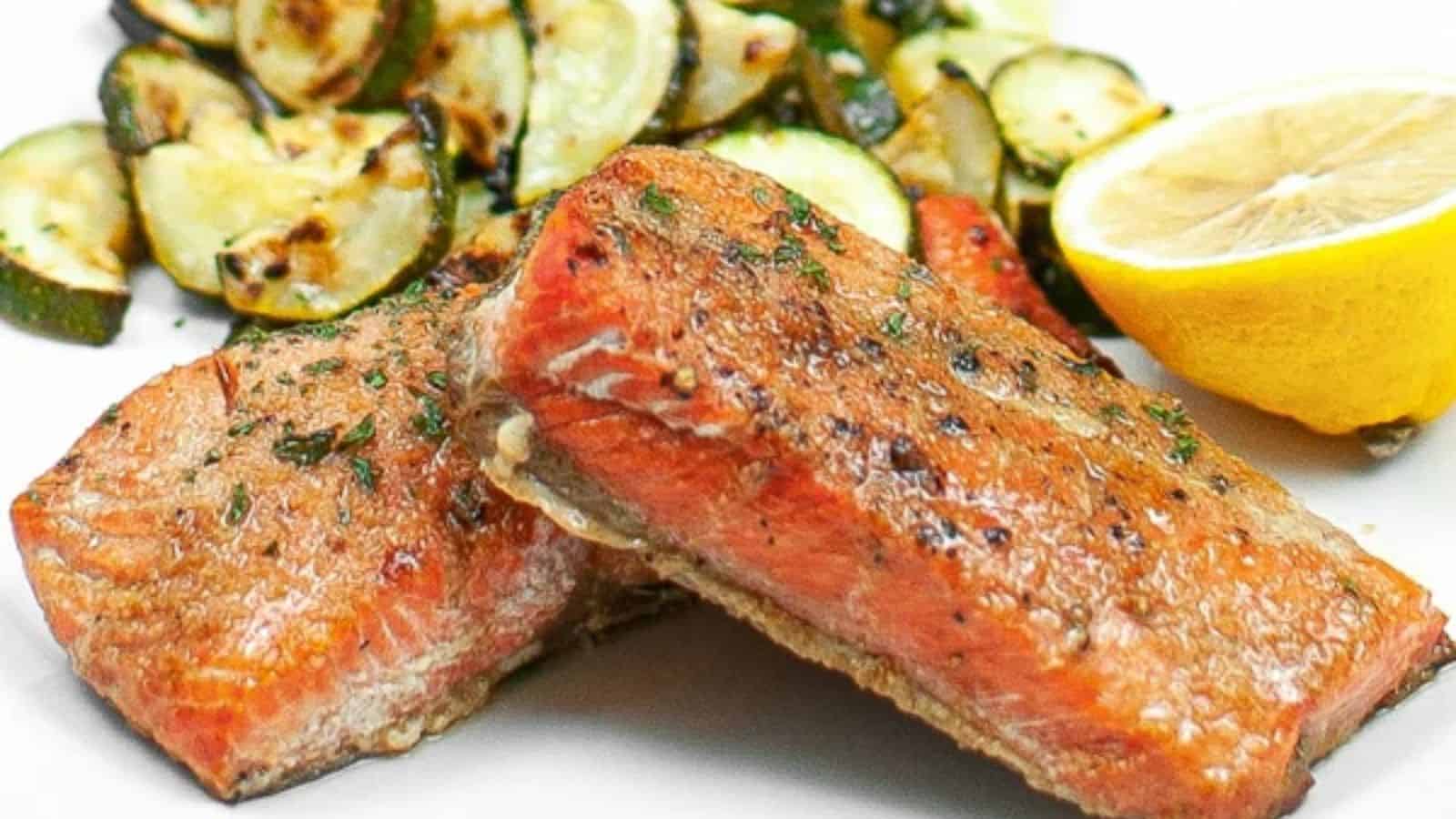 Honey garlic salmon fillets glazed and served on a white plate with garnish.