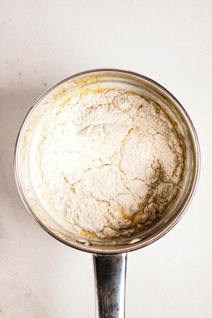 Flour and melted butter mixture in a metal saucepan, viewed from above on a light countertop—perfect as the base for a delicious Gluten Free Almond Eclair Cake.