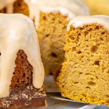A sliced bundt cake with creamy glaze drizzled on top, showing its moist, golden interior.
