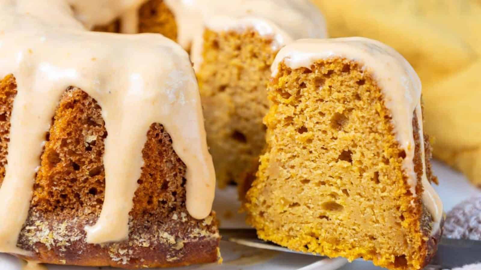 A pumpkin bundt cake with vanilla glaze on a white plate.