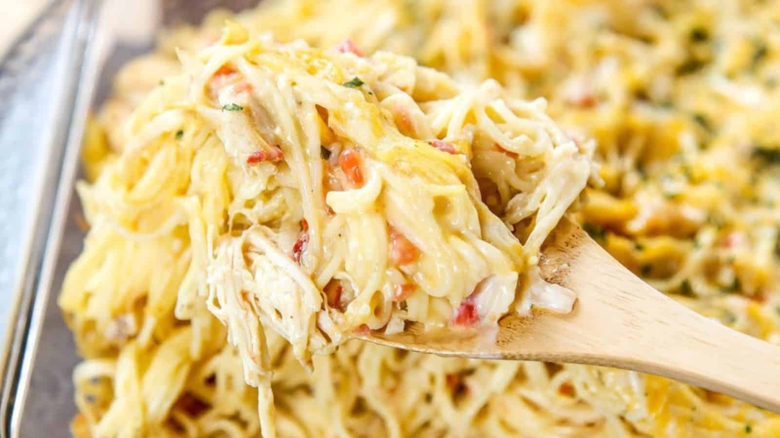 A wooden spoon lifting spaghetti our a casserole dish with a wooden spoon.