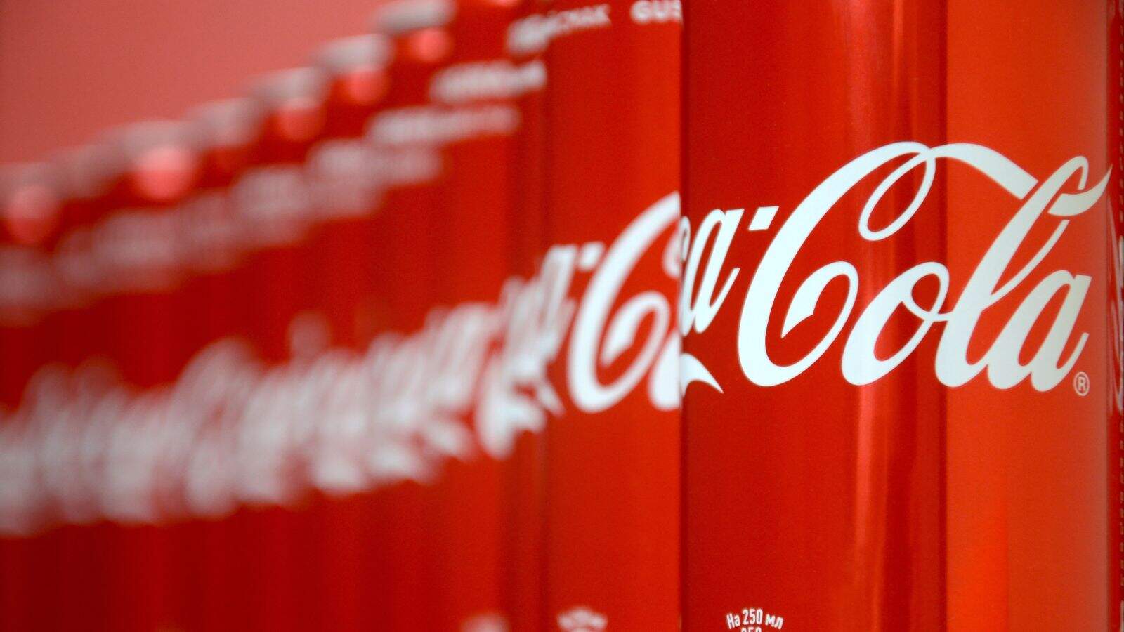 Rows of red Coca-Cola cans with white logo, shown in close-up and fading into the background&mdash;a reminder of recent Coca-Cola recalls over possible metal contamination.