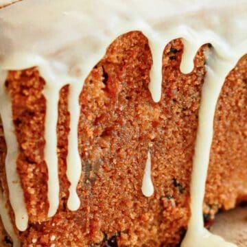Close-up of a loaf cake with white icing dripping down the sides.