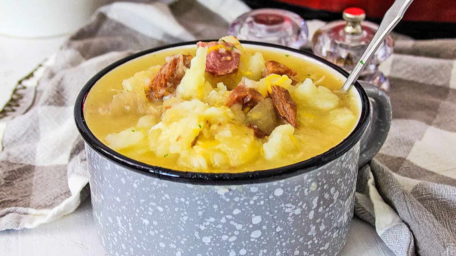Ham and Potato soup in a gray and white bowl with a spoon.