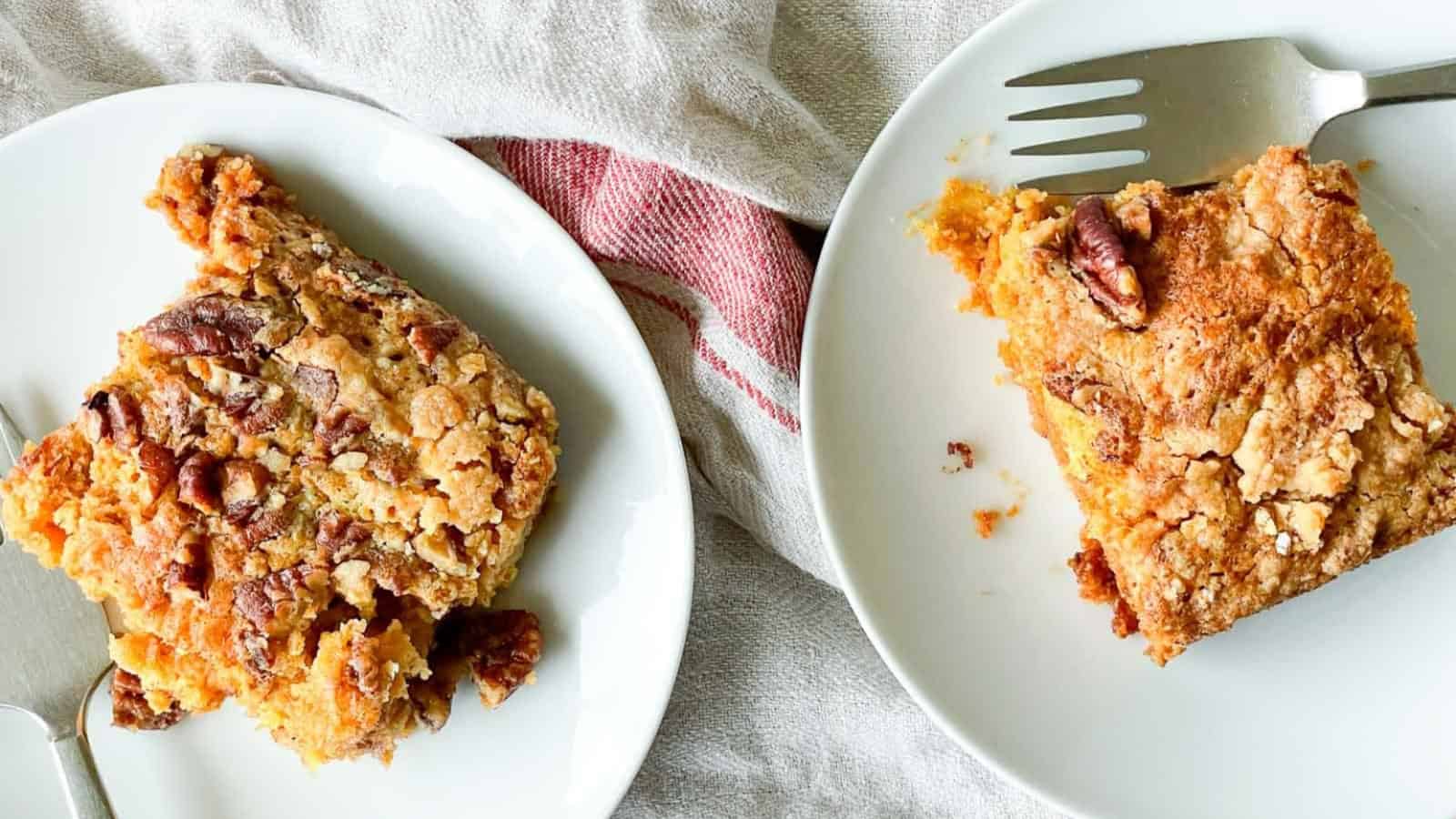 Slices of pumpkin crunch cake in white plates with forks on the side.