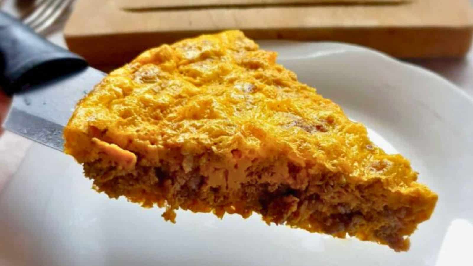 A person cutting a piece out of a casserole.