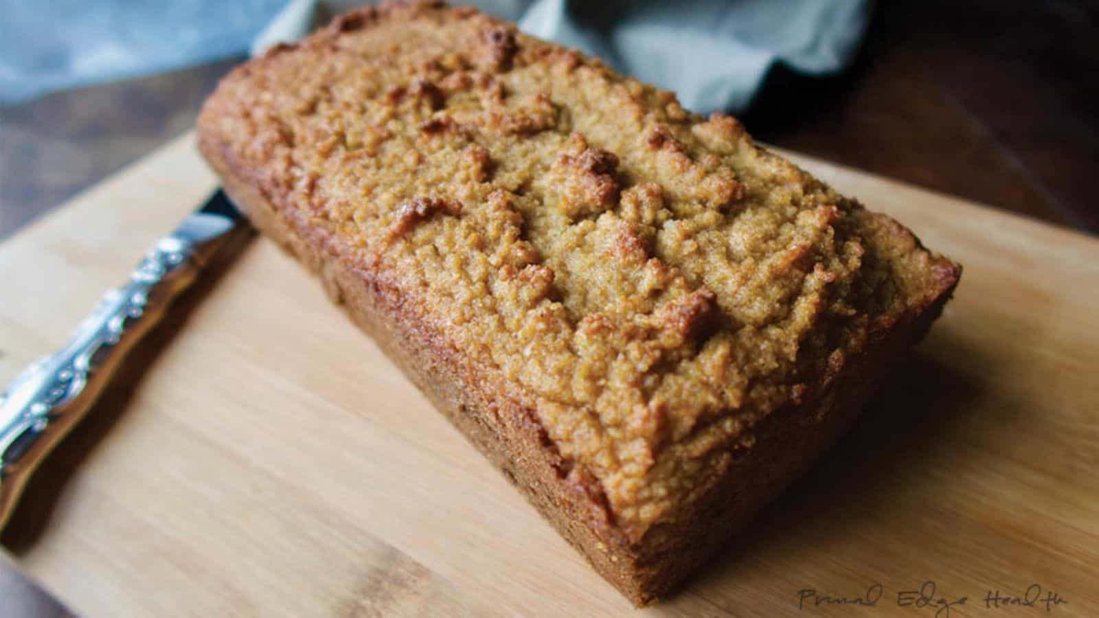 Gingerbread on wooden cutting board with knife.