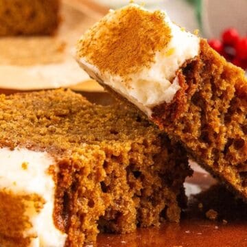 Two slices of spiced gingerbread cake with white frosting on a plate, garnished with cinnamon.