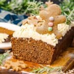 A sliced Gingerbread Loaf topped with creamy frosting, a cheerful gingerbread man, and festive cookie decorations.
