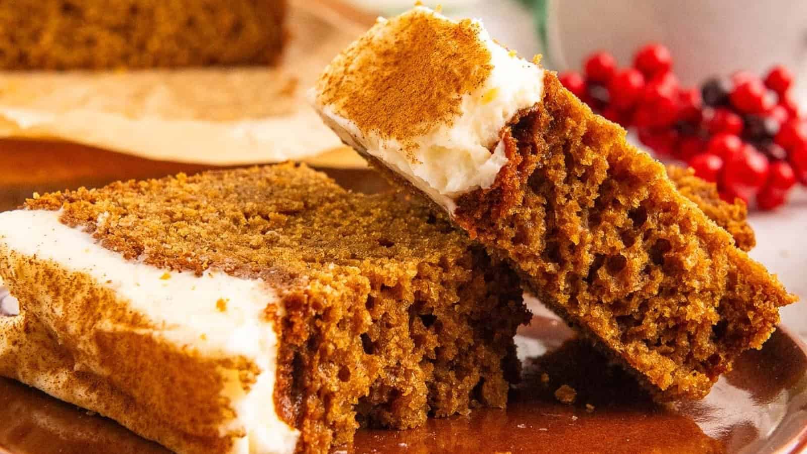 Two slices of spiced gingerbread cake with white frosting on a plate, garnished with cinnamon.