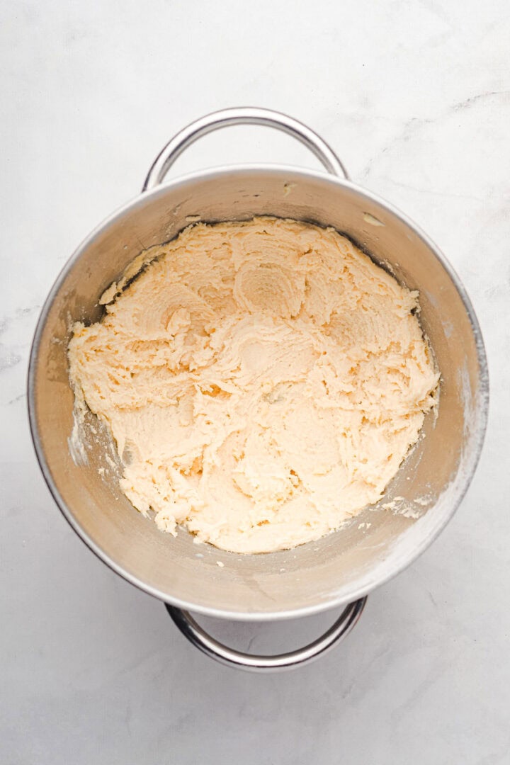 A metal mixing bowl with creamed butter and sugar on a light marble surface, ready to be transformed into delicious gingerbread muffins.