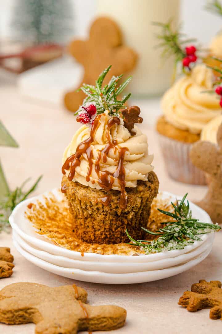 Gingerbread cupcake with caramel drizzle, frosting, and festive holiday decorations on a white plate—perfect for fans of gingerbread muffins.