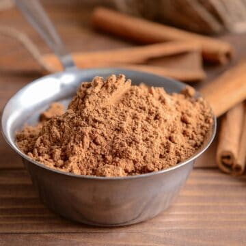 A metal bowl filled with ground cinnamon, amid concerns over harmful levels of lead found in 16 brands of ground cinnamon, sits on a wooden table next to whole cinnamon sticks.