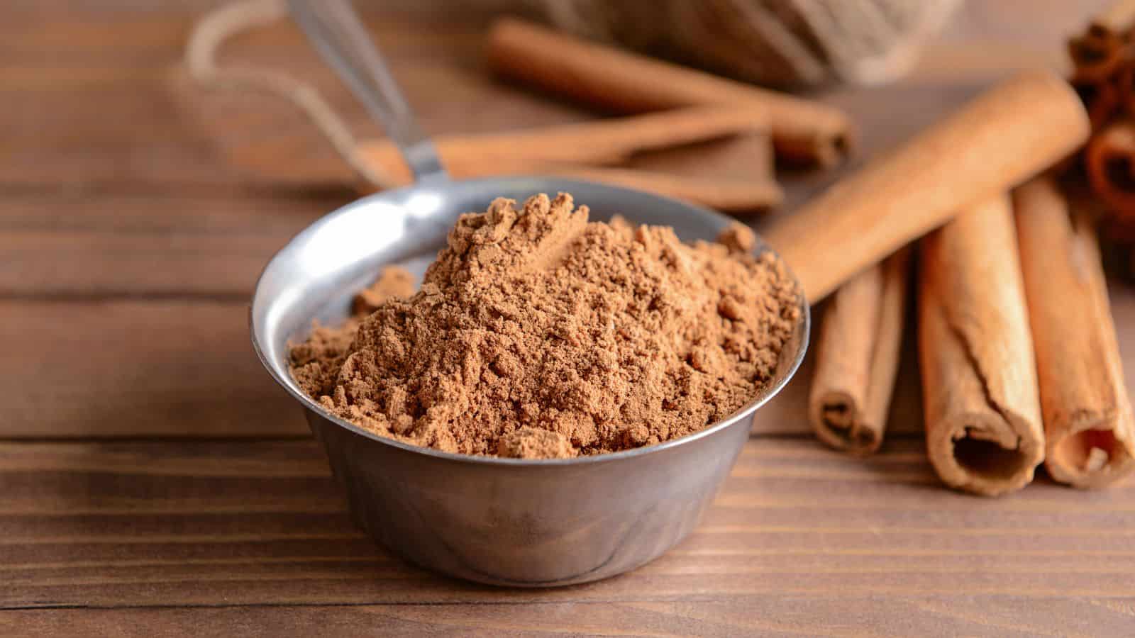 A metal bowl filled with ground cinnamon, amid concerns over harmful levels of lead found in 16 brands of ground cinnamon, sits on a wooden table next to whole cinnamon sticks.