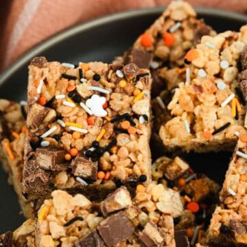 Enjoy Halloween Candy Rice Krispies—crispy rice treats topped with chocolate chunks and festive orange, black, and white sprinkles for the perfect spooky snack.