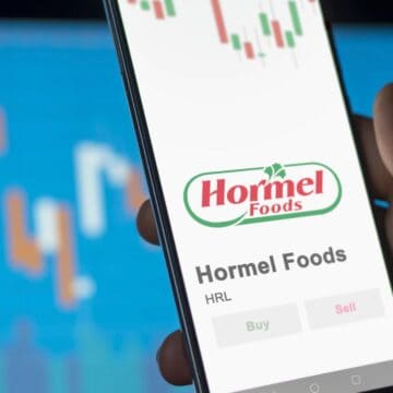 A phone displays Hormel Foods stock info with buy and sell options; graphs are blurred in the background.