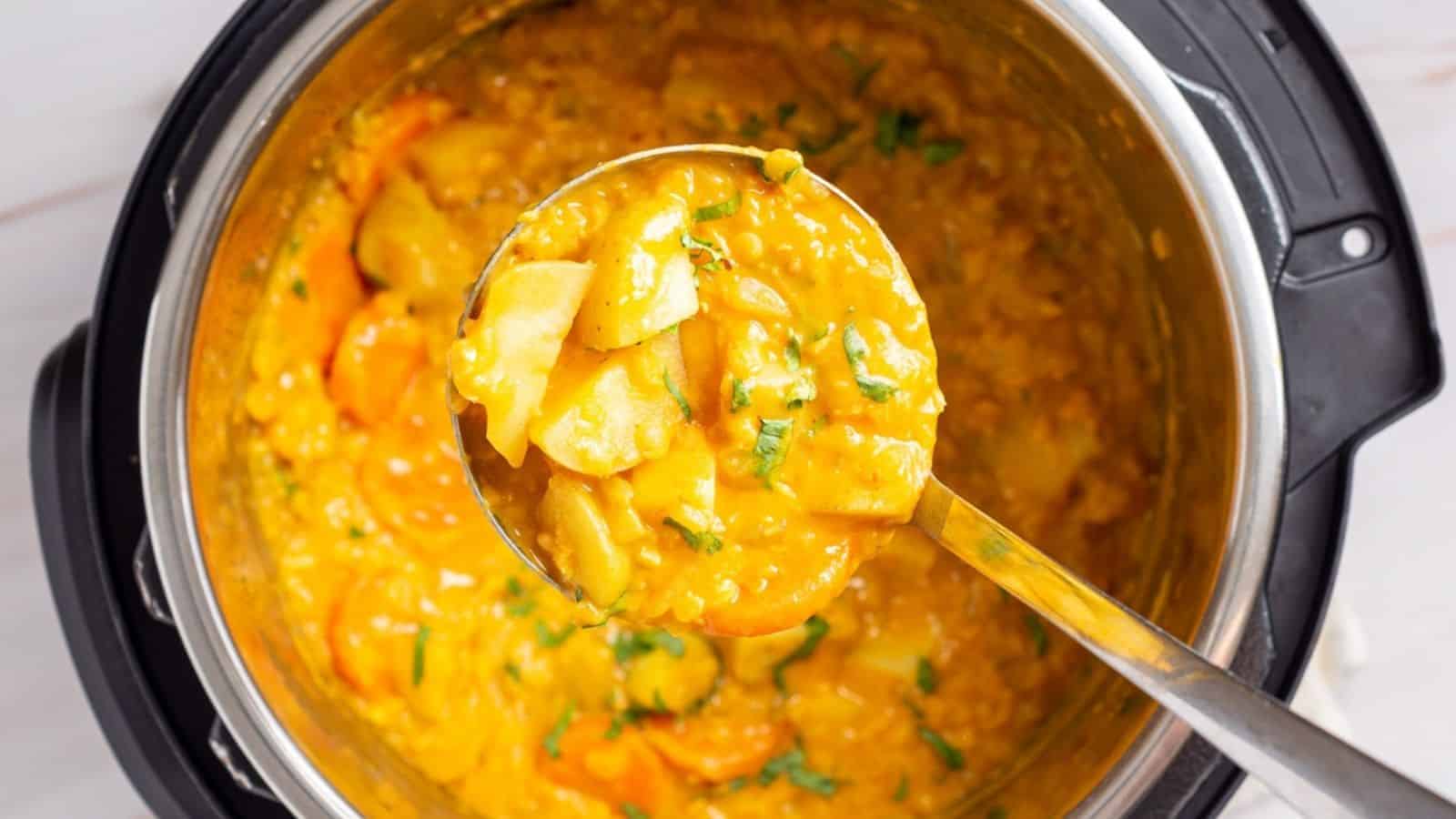 An overhead image of instant pot mulligatawny soup being scoop out from the pot.