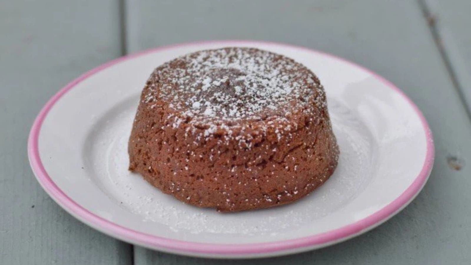 Image shows a fork pulling a bite from a molten chocolate cake on a white plate.