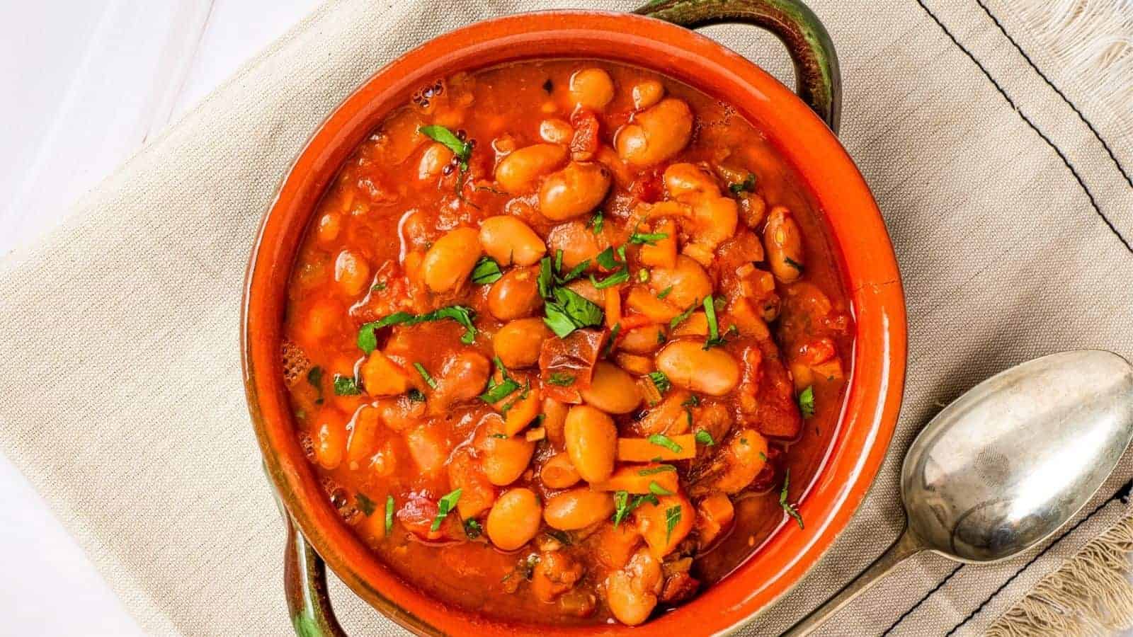 An overhead image of pinto bean soup in a green bowl with a spoon on the side.