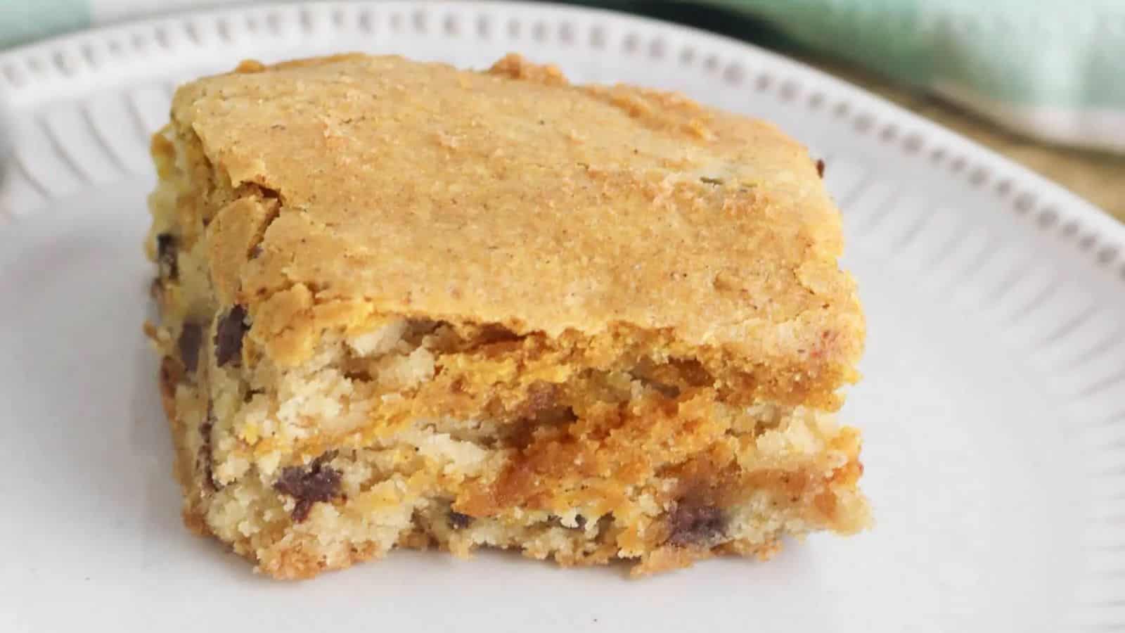 A single square of blondie dessert with chocolate chips on a white plate.