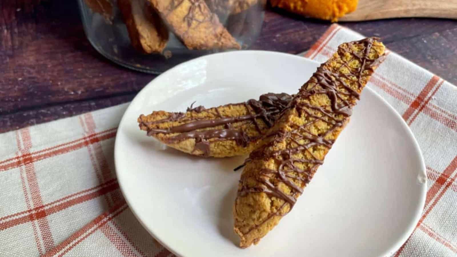 A tray of pumpkin biscotti with chocolate drizzle on them.