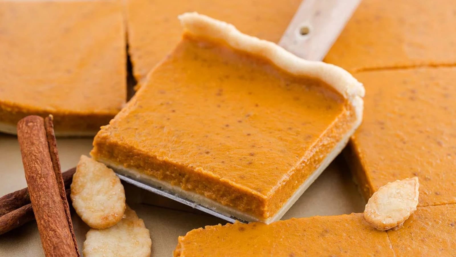 A slice of pumpkin slab pie is being picked up.