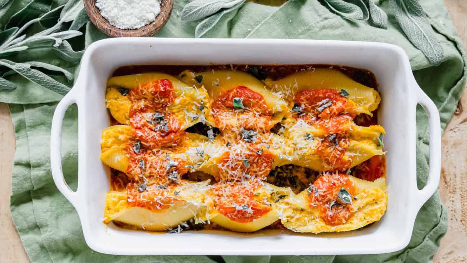 Pumpkin stuffed shells in a white dish with a spoon.