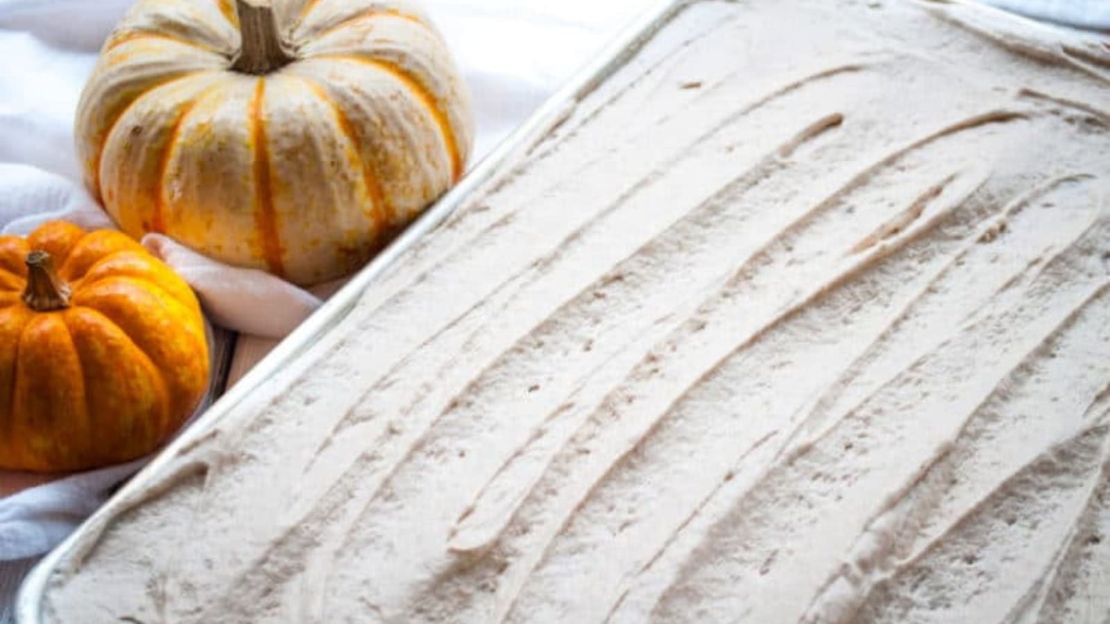 Pumpkin cake in a pan surrounded by pumpkins.