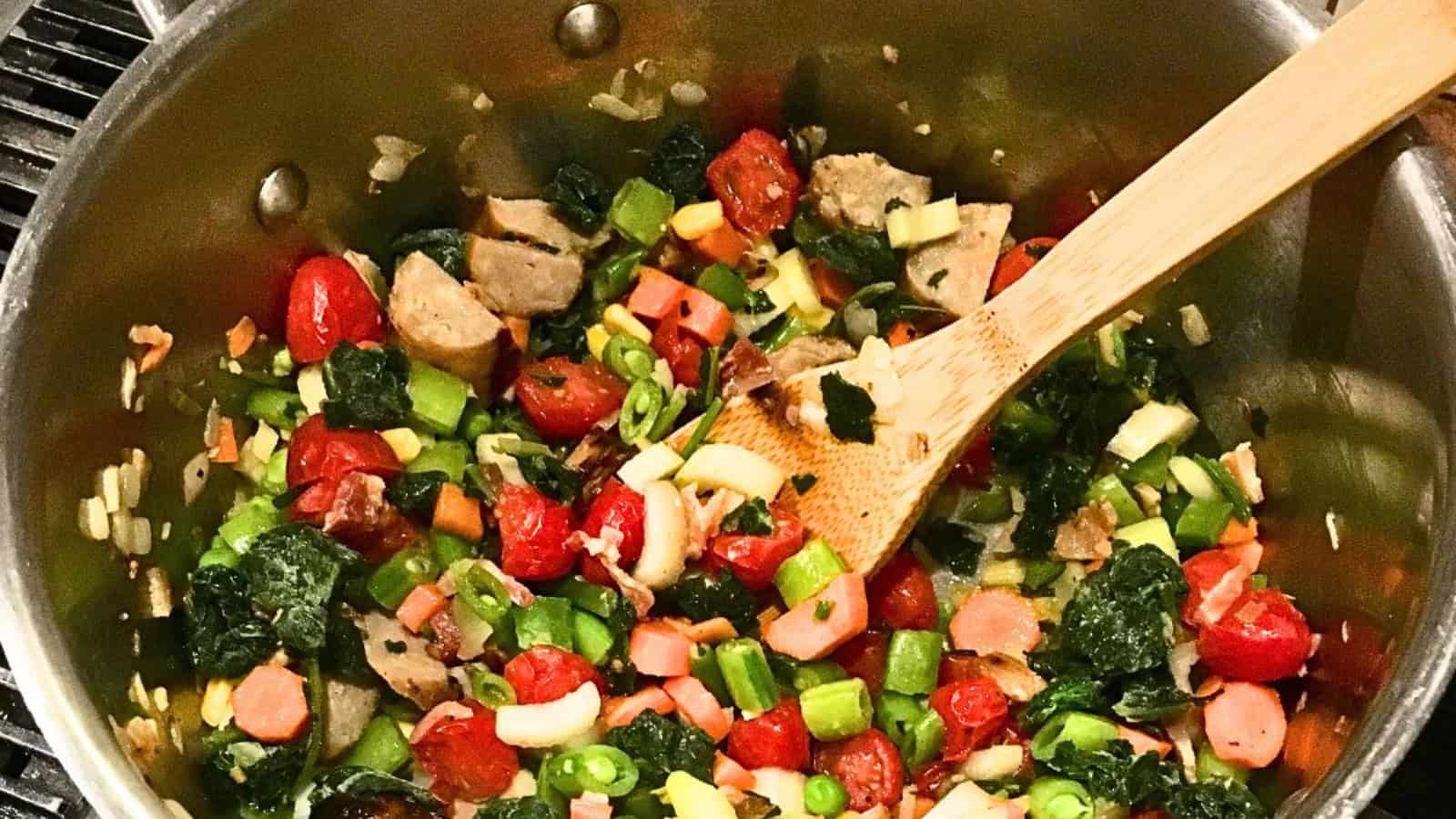 Sausage, kale and bean soup in pot with a wooden spoon.