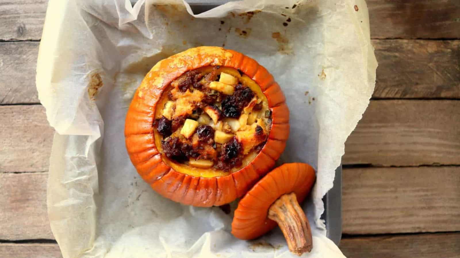 Baked stuffed pumpkin filled with a savory mixture, placed on parchment in a baking dish, with lid beside it.