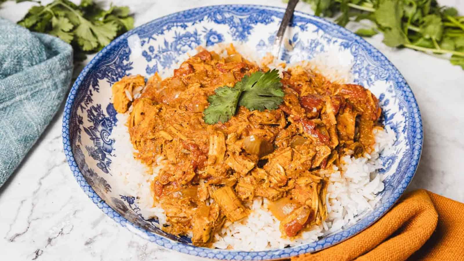 Shredded chicken in a tomato-based sauce served over white rice, garnished with fresh cilantro.