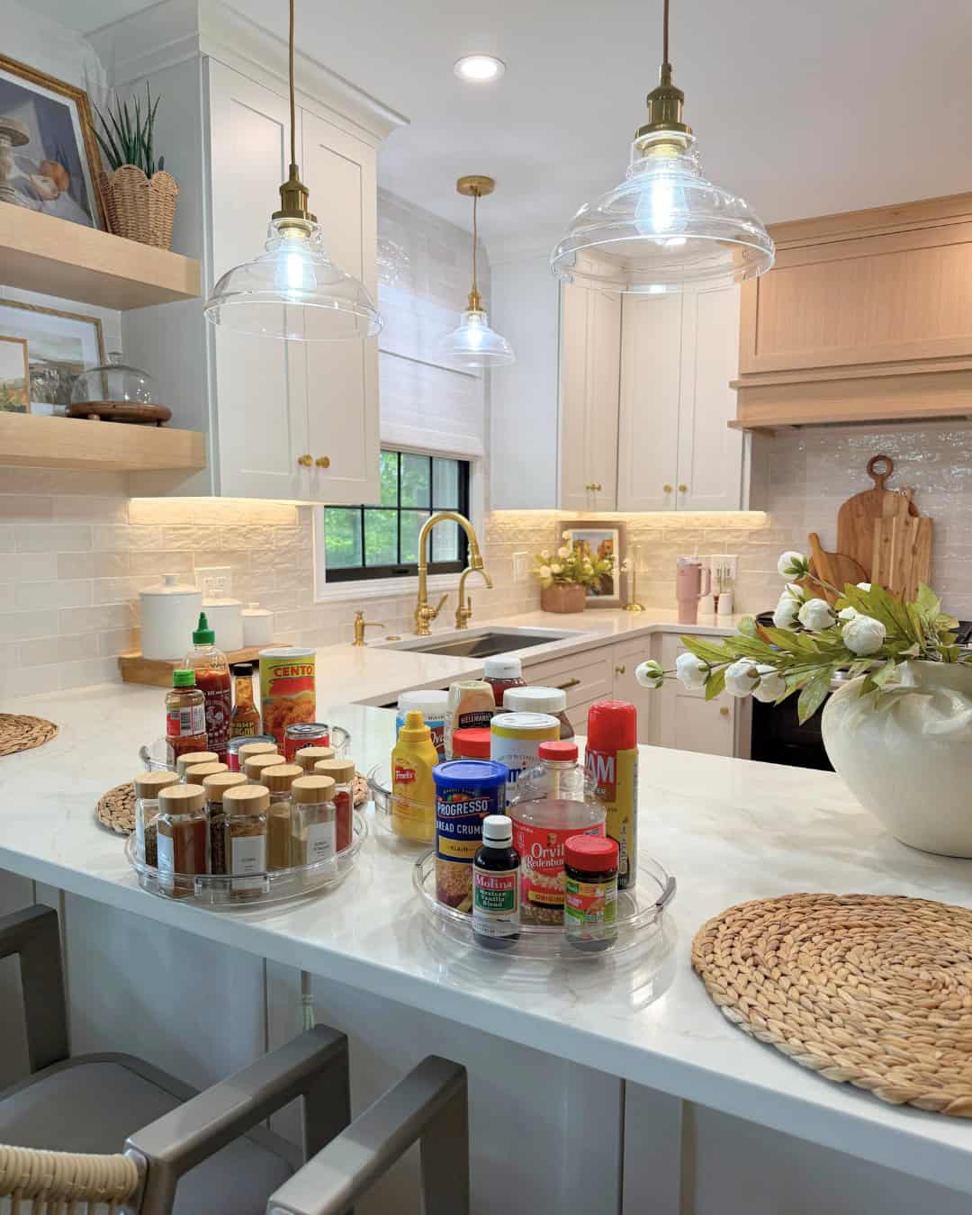 Modern kitchen with spices and condiments organized on two turntables on a white marble island countertop.